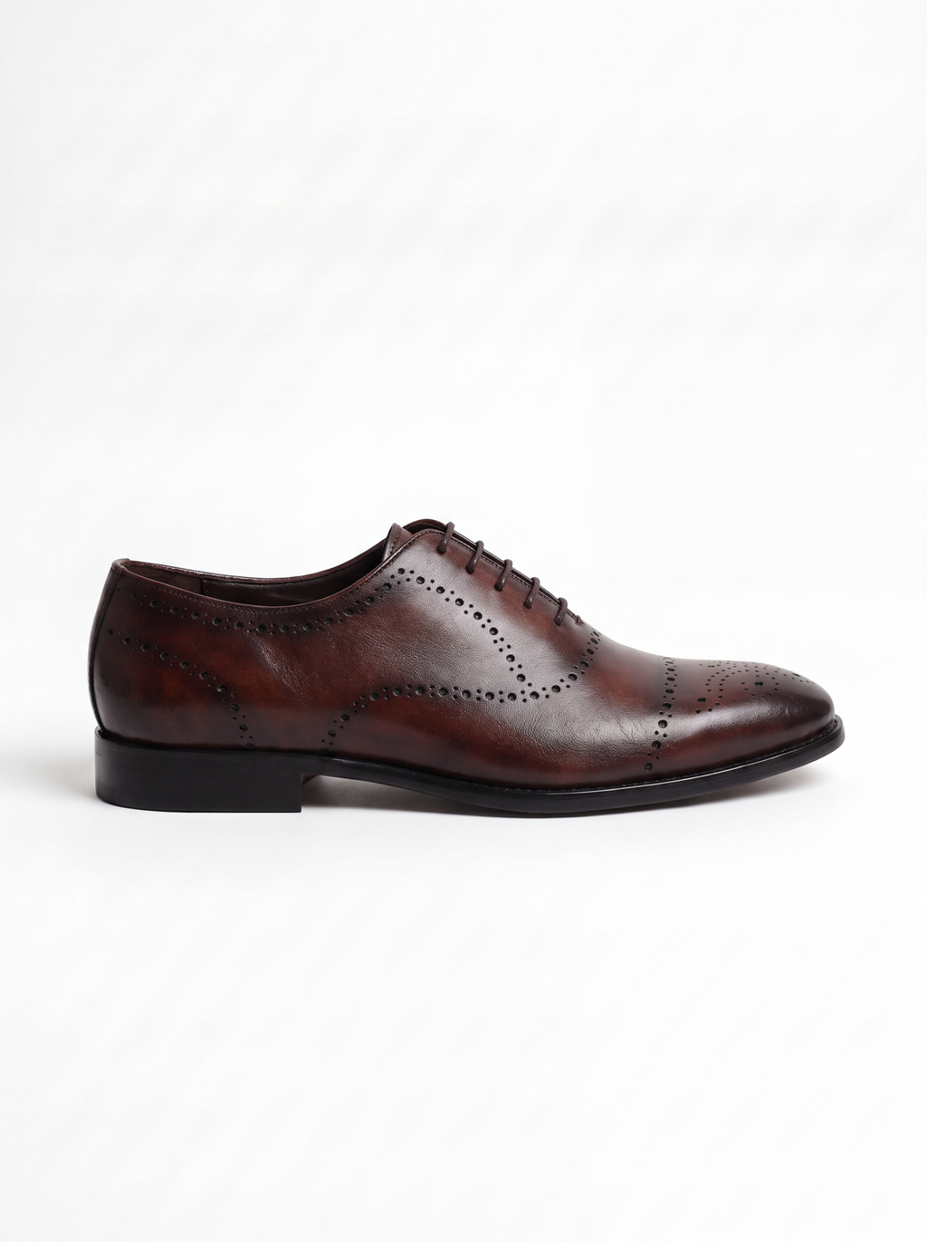 A single dark brown oxford wingtip shoe with decorative brogue perforations, shown in a side profile against a clean white background.